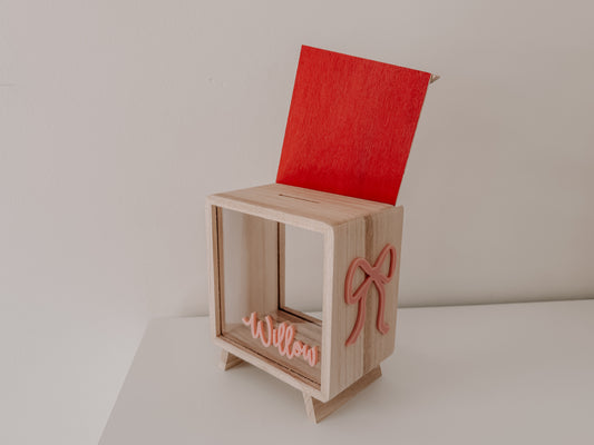 Wooden Money box for girls with pink ribbon bow personalised with childs name and red backing wood 