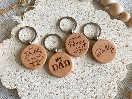 Round Wooden keychains with engraved messages on a textured surface. Engraved Keyring gift for Father's Day